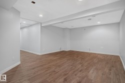 Spacious room featuring wood-finish flooring, recessed lighting, neutral paint, white trim, and exposed ceiling beams - 
