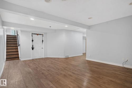 Spacious finished room featuring wood-finish flooring, recessed lighting, light gray walls, and white trim - 1071 Millbourne Road Nw, Edmonton, AB 
