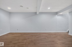 Spacious room featuring light blue walls, wood-finish flooring, recessed lighting, and white baseboards - 