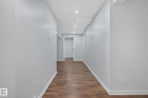 Hallway featuring wood-finish flooring, recessed lighting, and crisp white trim - 1071 Millbourne Road Nw, Edmonton, AB 