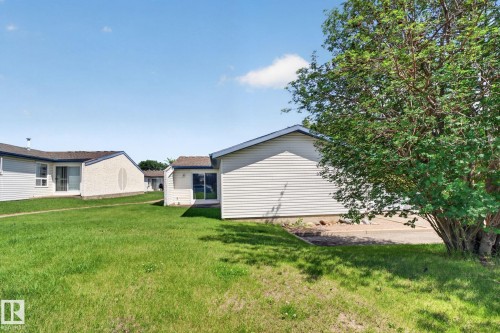 Expansive green space featuring a mature tree, siding exterior, and a visible roofline - 1071 Millbourne Road Nw, Edmonton, AB 