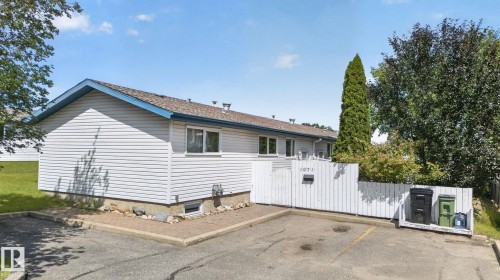 Exterior featuring white horizontal siding, a blue-trimmed roofline, and multiple windows - 1071 Millbourne Road Nw, Edmonton, AB 