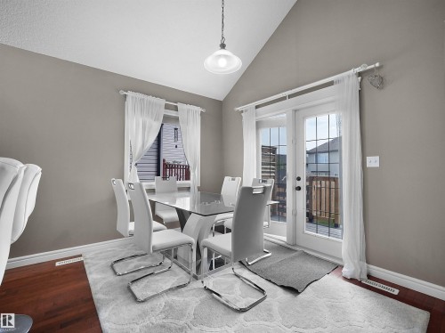 Dining area featuring wood-finish flooring, a window with white trim, and a patio door with integrated grids - 4021 158 Avenue Nw, Edmonton, AB - Indoor Photo Showing Dining Room
