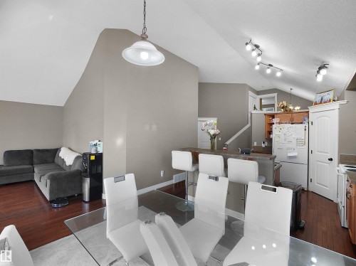 Open-concept interior featuring wood-finish flooring, vaulted ceilings, and a breakfast bar with seating - 4021 158 Avenue Nw, Edmonton, AB - Indoor