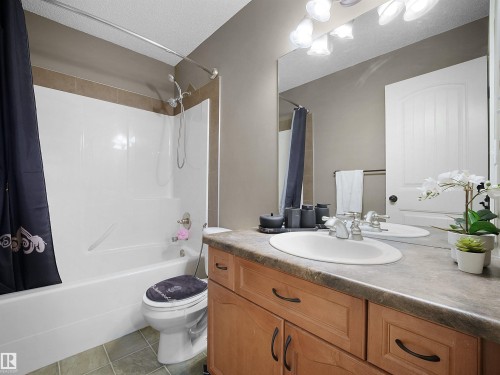 Full bathroom featuring a single vanity with a laminate countertop, light wood cabinetry, and a mirrored wall - 4021 158 Avenue Nw, Edmonton, AB - Indoor Photo Showing Bathroom