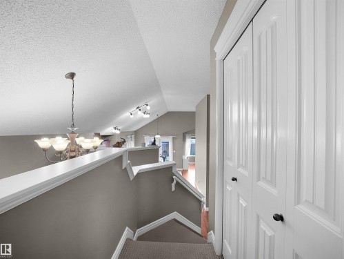 Carpeted staircase with white trim, leading to an upper level with an open railing overlooking a lower space - 4021 158 Avenue Nw, Edmonton, AB - Indoor Photo Showing Other Room