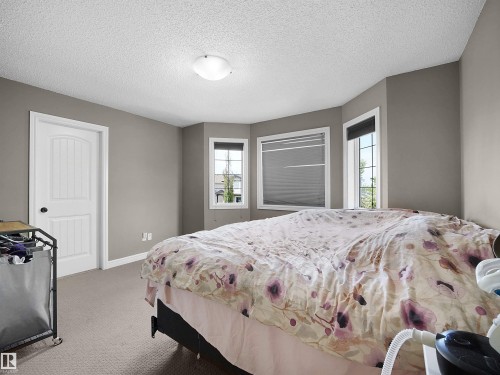 Carpeted room featuring a ceiling-mounted light fixture, multiple windows with blinds, and neutral wall paint - 4021 158 Avenue Nw, Edmonton, AB - Indoor Photo Showing Bedroom