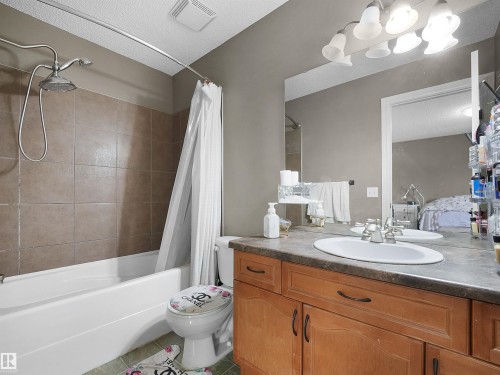 Bathroom featuring a built-in vanity with wood-finish cabinetry, an integrated sink, and a large wall-mounted mirror - 4021 158 Avenue Nw, Edmonton, AB - Indoor Photo Showing Bathroom