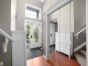 Foyer featuring wood-finish flooring, a white entry door with decorative glass, an overhead transom window, and mirrored closet doors - 4021 158 Avenue Nw, Edmonton, AB  - Indoor Photo Showing Other Room 