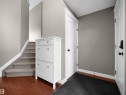 Entryway featuring warm wood-finish flooring, staircase with carpeted treads, and painted paneled doors with black hardware - 4021 158 Avenue Nw, Edmonton, AB  - Indoor Photo Showing Other Room 