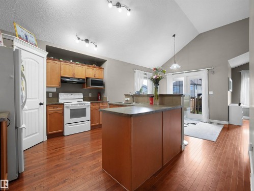 Kitchen featuring warm wood cabinetry, stainless steel appliances, and a central island with a contrasting countertop - 4021 158 Avenue Nw, Edmonton, AB - Indoor Photo Showing Kitchen