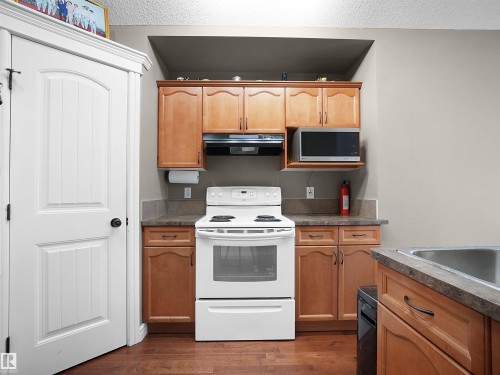 Compact kitchen area featuring wood-finish flooring and light wood cabinetry - 4021 158 Avenue Nw, Edmonton, AB - Indoor Photo Showing Kitchen