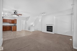 Open-concept living area featuring a built-in fireplace with a white mantel, track lighting, and a ceiling fan - 