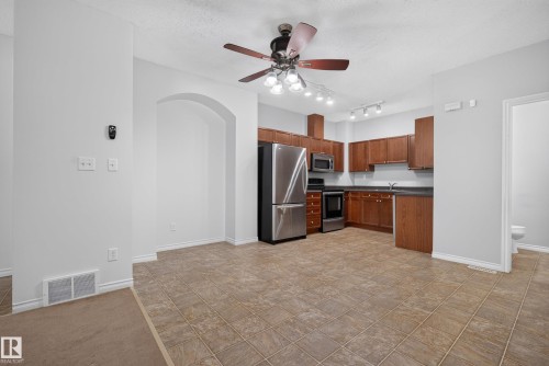 Open concept living area featuring a kitchen with wood cabinetry and stainless steel appliances - #113 3010 33 Av Nw, Edmonton, AB 