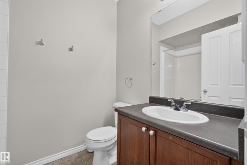 Bathroom featuring a dark wood-finish vanity with an integrated sink, a dark countertop, and a large wall-mounted mirror - #113 3010 33 Av Nw, Edmonton, AB 