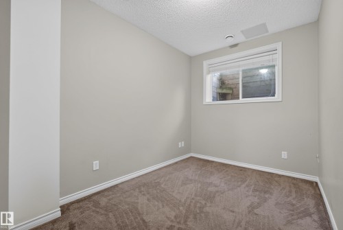 Neutral-toned room featuring a single window with blinds, light gray walls, and brown patterned carpet - #113 3010 33 Av Nw, Edmonton, AB 