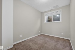 Neutral-toned room featuring a single window with blinds, light gray walls, and brown patterned carpet - 
