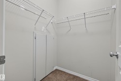Walk-in closet featuring wire shelving, white painted walls, and textured carpet flooring - 