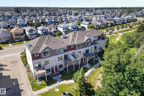 Contemporary multi-level townhome featuring a multi-tone exterior, private balconies with glass railings, and a gabled roofline - #113 3010 33 Av Nw, Edmonton, AB 