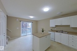 Kitchen area featuring white cabinetry, light-toned countertops, and an integrated dishwasher - 