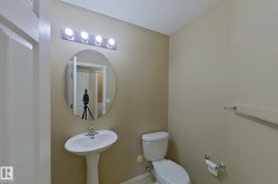 Pedestal sink with a polished chrome faucet, oval mirror, and a four-bulb vanity light fixture - 