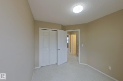 Neutral-toned room with light-colored carpeting, a ceiling-mounted light fixture, and white bi-fold closet doors - 
