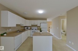 Kitchen featuring white cabinetry, light-toned countertops, a central island, and white appliances including a refrigerator, stove, and dishwasher - 