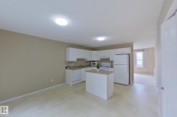 Open-concept kitchen featuring white cabinetry, light-toned countertops, and an island with counter space - 