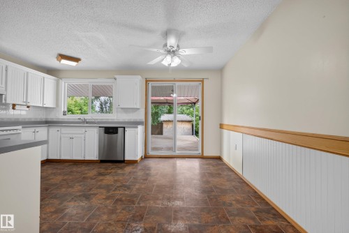 Kitchen area featuring white cabinetry, a stainless steel dishwasher, and a tile backsplash - 3 Bristow Crescent, Spruce Grove, AB - Indoor Photo Showing Kitchen