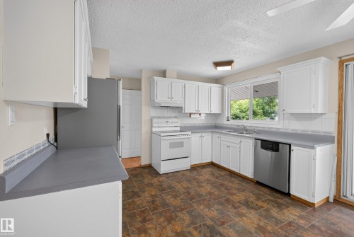 Kitchen featuring white cabinetry, gray countertops, white appliances, stainless steel dishwasher, and tiled flooring - 3 Bristow Crescent, Spruce Grove, AB - Indoor Photo Showing Kitchen With Double Sink