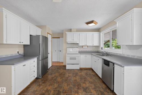 Bright kitchen featuring white cabinetry, gray countertops, and a tiled backsplash - 3 Bristow Crescent, Spruce Grove, AB - Indoor Photo Showing Kitchen With Double Sink