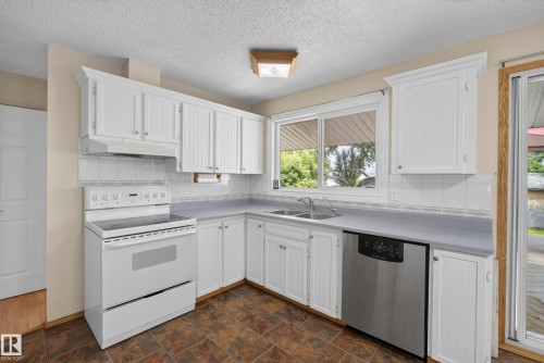 Kitchen featuring white cabinetry, tile backsplash, laminate countertops, stainless steel dishwasher, and wood-finish flooring - 3 Bristow Crescent, Spruce Grove, AB - Indoor Photo Showing Kitchen With Double Sink