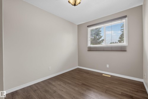 Spacious room featuring wood-finish flooring, neutral wall paint, white trim, and a window with blinds - 3 Bristow Crescent, Spruce Grove, AB - Indoor Photo Showing Other Room