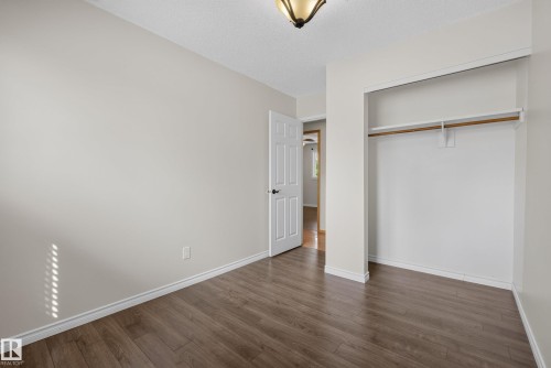 Spacious interior room featuring wood-finish flooring, white baseboards, and a built-in closet with a hanging rod - 3 Bristow Crescent, Spruce Grove, AB - Indoor Photo Showing Other Room