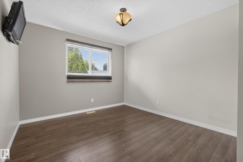 Neutral-toned room featuring wood-finish flooring, a window with horizontal blinds, and a ceiling-mounted light fixture - 3 Bristow Crescent, Spruce Grove, AB - Indoor Photo Showing Other Room