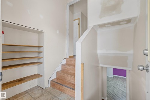 Interior staircase with wood-finish treads and risers, featuring a built-in shelving unit with five wood-finish shelves - 3 Bristow Crescent, Spruce Grove, AB - Indoor Photo Showing Other Room