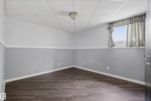 Room featuring wood-finish flooring, drop ceiling, and wainscoting with a window providing natural illumination - 3 Bristow Crescent, Spruce Grove, AB - Indoor