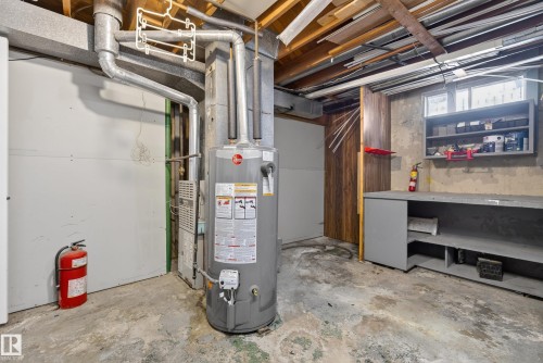 Utility area featuring a water heater, exposed ceiling joists, and a built-in workbench with shelving - 3 Bristow Crescent, Spruce Grove, AB - Indoor Photo Showing Basement