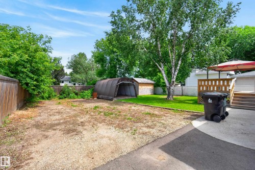 Spacious backyard featuring a wood fence, mature trees, a detached storage shed, a slatted wood deck, and a concrete patio - 3 Bristow Crescent, Spruce Grove, AB - Outdoor