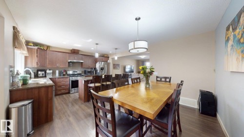 Open-concept dining and kitchen area featuring wood-finish flooring, recessed lighting, and a drum pendant light fixture - 6824 Evans Wynd Nw, Edmonton, AB - Indoor Photo Showing Other Room