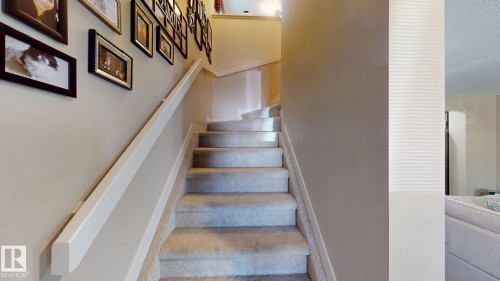 Carpeted staircase with a white handrail - 6824 Evans Wynd Nw, Edmonton, AB - Indoor Photo Showing Other Room