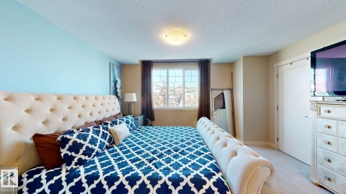 Bedroom featuring a window with grid detailing, neutral-toned curtains, and a flush-mount ceiling light fixture - 6824 Evans Wynd Nw, Edmonton, AB - Indoor Photo Showing Bedroom