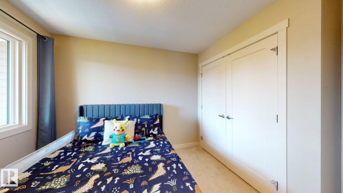 Neutral-toned room featuring a window with white trim, a textured ceiling, and light-colored carpeting - 6824 Evans Wynd Nw, Edmonton, AB - Indoor Photo Showing Bedroom