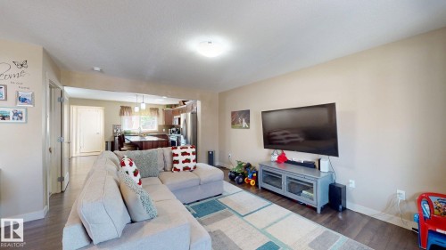 Spacious living area featuring wood-finish flooring, neutral wall tones, and recessed lighting - 6824 Evans Wynd Nw, Edmonton, AB - Indoor Photo Showing Living Room