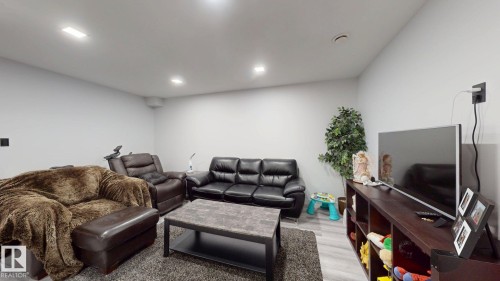 Spacious living area featuring light gray walls, recessed lighting, and wood-finish flooring - 6824 Evans Wynd Nw, Edmonton, AB - Indoor Photo Showing Basement