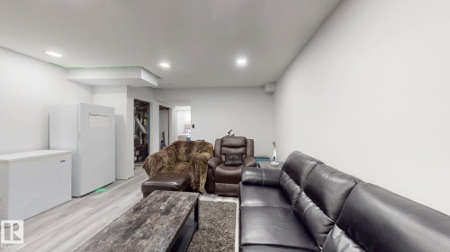 Recessed lighting illuminates an interior space featuring wood-finish flooring and white painted walls - 6824 Evans Wynd Nw, Edmonton, AB - Indoor