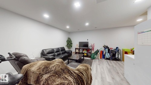 Spacious room featuring light gray walls, recessed lighting, and wood-finish flooring - 6824 Evans Wynd Nw, Edmonton, AB - Indoor