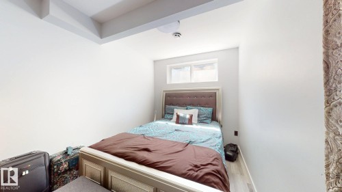 Crisp white walls define this bedroom space, featuring light wood-finish flooring - 6824 Evans Wynd Nw, Edmonton, AB - Indoor Photo Showing Bedroom