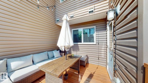 Outdoor deck featuring wood-finish flooring, two-tone siding, an exterior door, and an exterior light fixture - 6824 Evans Wynd Nw, Edmonton, AB - Outdoor With Exterior
