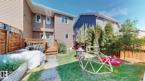 Private backyard with a wooden deck, paver stone pathway, and mature trees - 6824 Evans Wynd Nw, Edmonton, AB - Outdoor